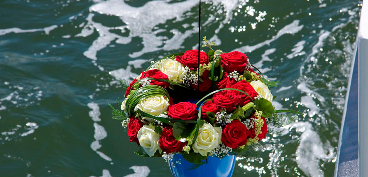 Blumengesteck auf dem Wasser bei einer Donau-Bestattung