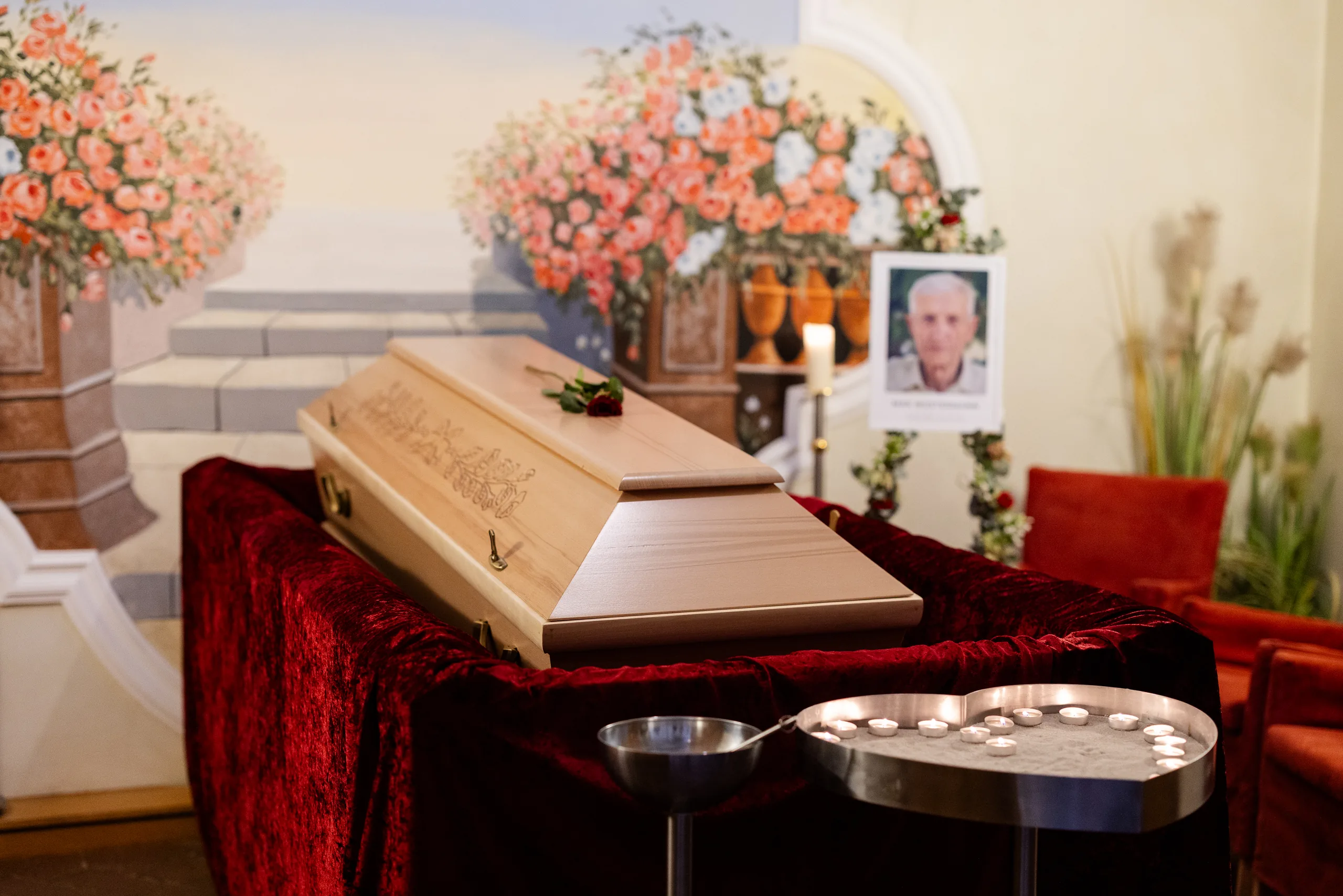 Hauseigener Abschiedsraum des Landshuter Bestattungsdiensts mit aufgebahrtem Sarg, Blumenschmuck und Kerzen – individuell nach den Wünschen der Angehörigen dekoriert