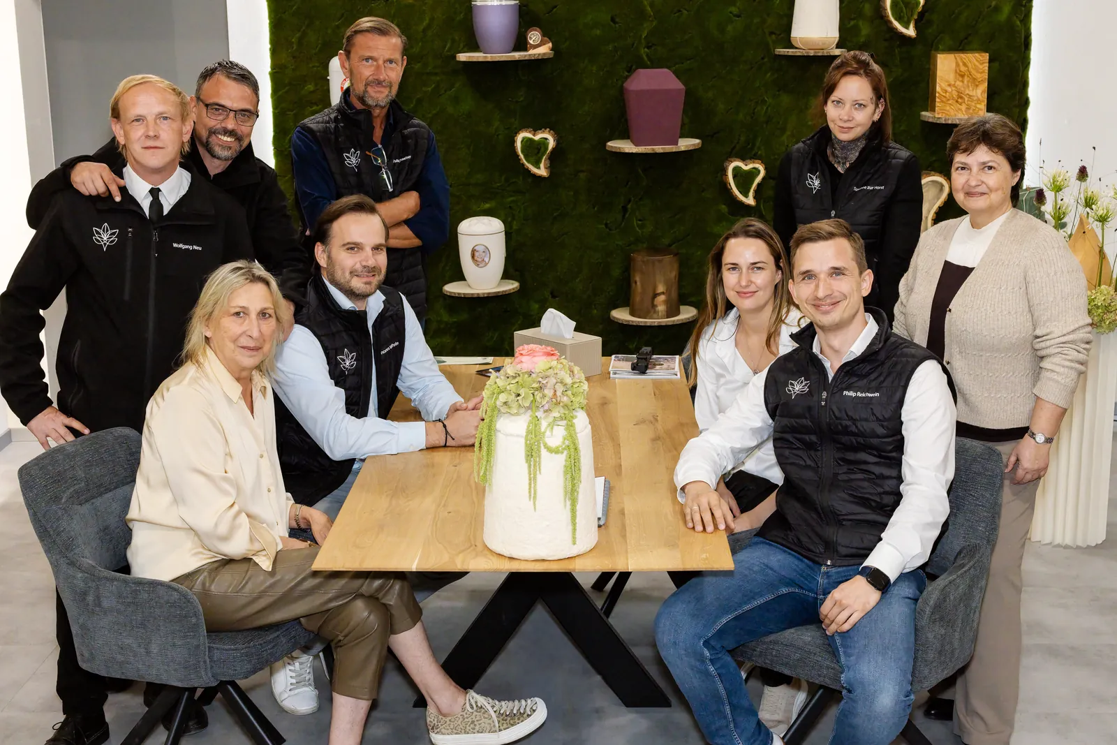 Das Team des Landshuter Bestattungsdiensts Gerlinde Reichwein 2026 am Besprechungstisch vor der Urnen-Mooswand
